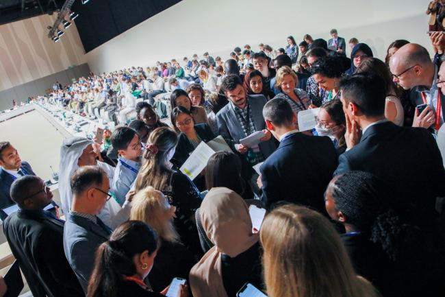 Delegates negotiating in a huddle during informal consultations on the Warsaw International Mechanism for Loss and Damage
